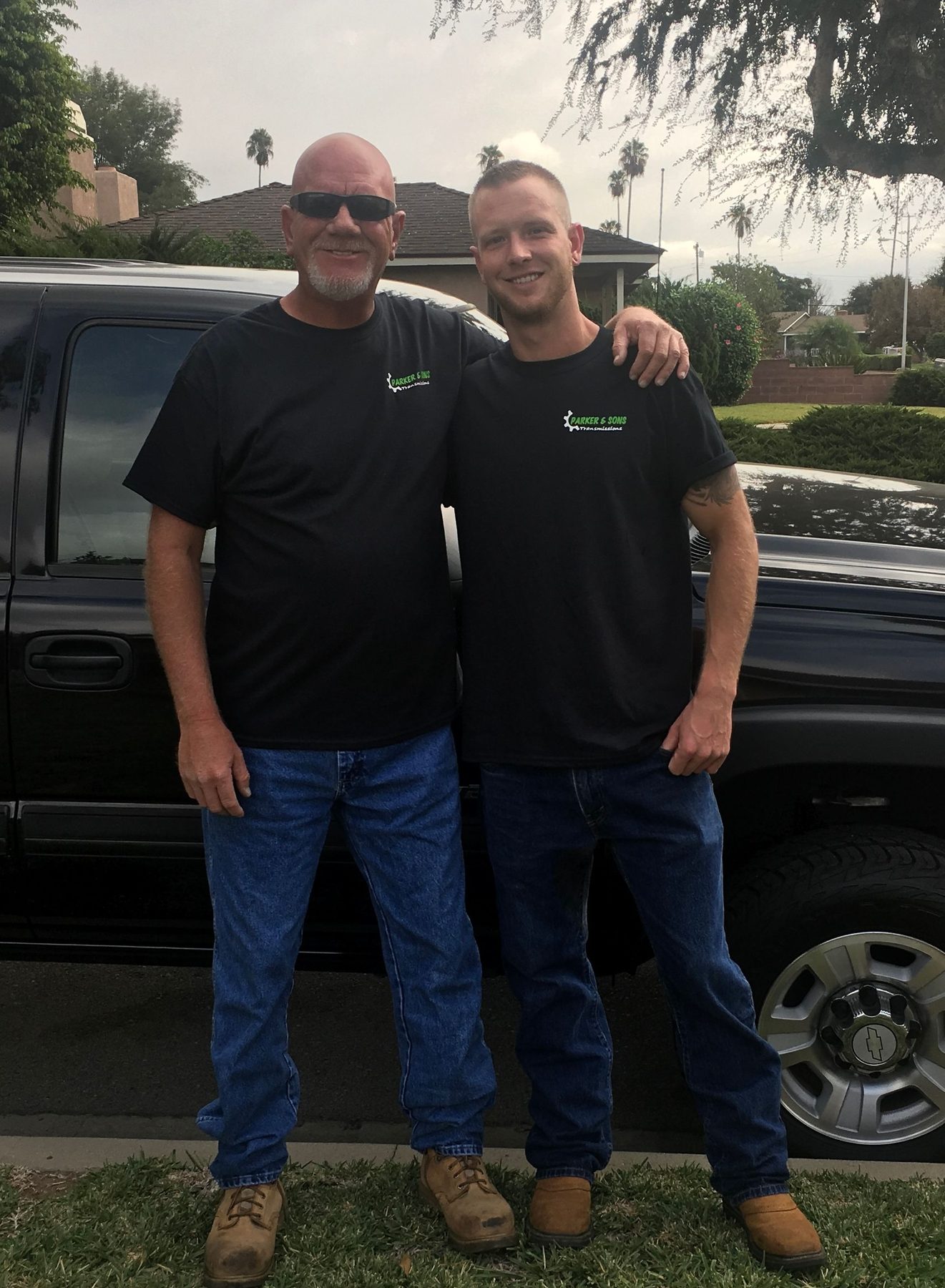 The father and son behind Parker & Sons Transmissions in company shirts outside the shop